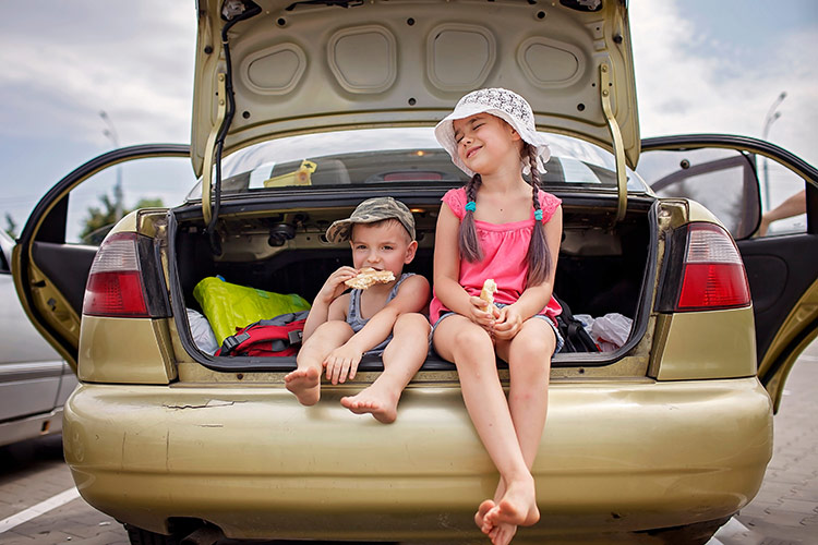 kids sitting in the boot of the car eating snacks