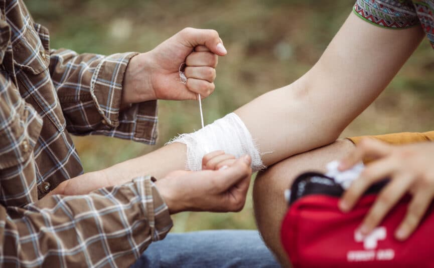 First Aid Kit A Person Wrapping Their Friends Injured Arm In Gauze