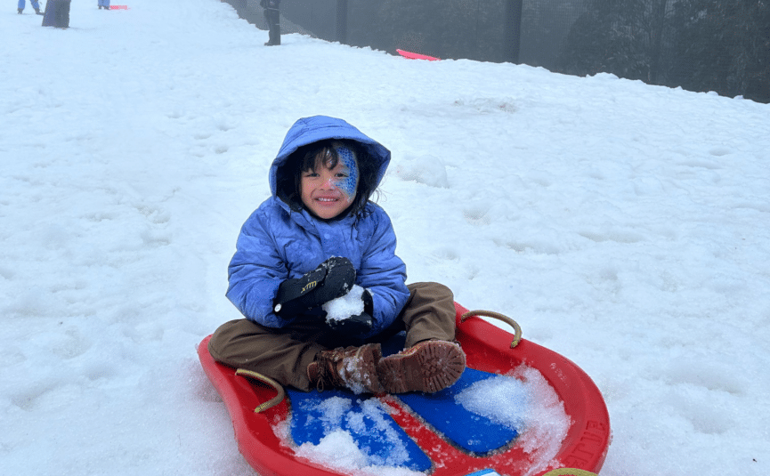 boy on toboggan with snow