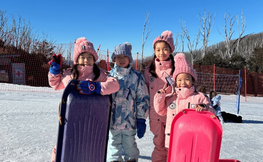 children in the snow with toboggans