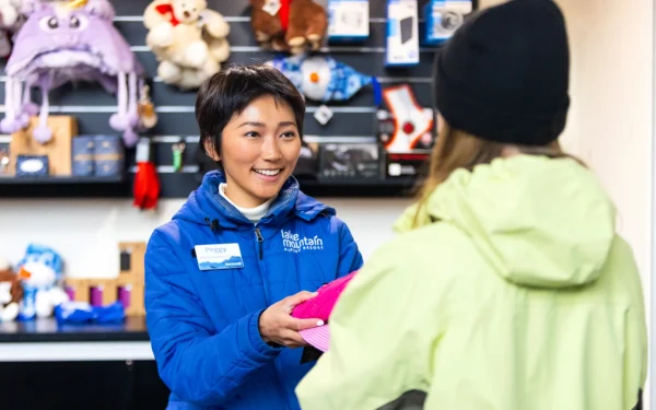 Employee hands an item to customer, with shelves of plush toys in the background.